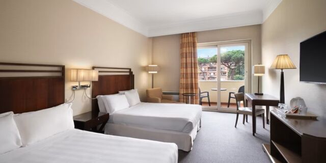 Hotel room at Crowne Plaza Rome -St. Peter's with two double beds, bedside lamps, a desk, chair, balcony and wall-mounted TV