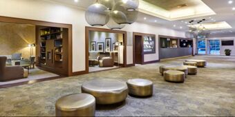 Spacious lobby of Crowne Plaza Rome - St. Peter's with metallic round seating, hanging lights, reception desk, and armchairs in alcoves
