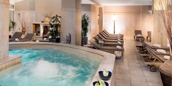 Indoor spa area with bubbling hot tub and multiple lounge chairs with towels at Crowne Plaza Rome -St. Peter's
