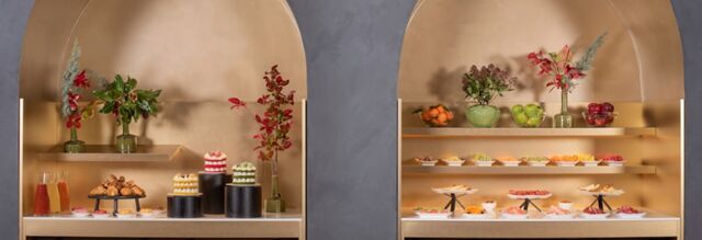 Buffet setup with pastries, cakes, fruit bowls, and flower arrangements at Hotel nhow Roma Vittorio Veneto