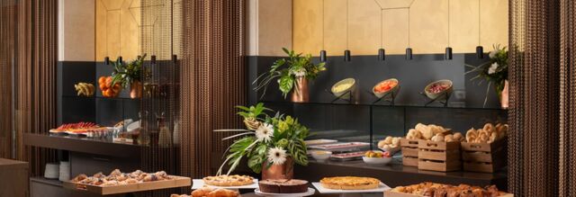 Buffet table with assorted pastries, cakes, fruits, and salads arranged in glasses and bowls at NH Collection Roma Centro