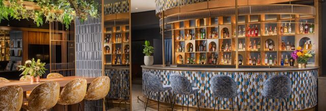 Bar area with patterned blue chairs and a wooden table with plants at NH Collection Roma Centro hotel interior