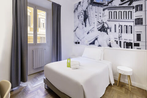 Double bed with white linens and two pillows, bedside table, large window with curtains, and mural in B&B Hotel Roma Italia Viminale