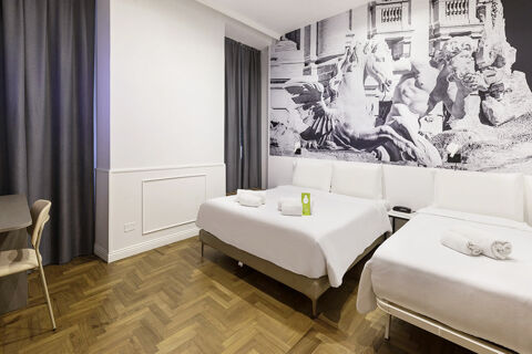 Hotel room at B&B Hotel Roma Italia Viminale with two beds, wooden floor, gray curtains, and a large mural of statues on the wall