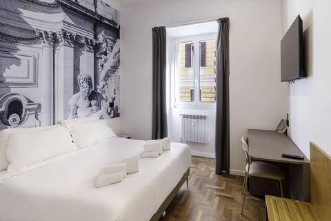 Hotel room at B&B Hotel Roma Italia Viminale with king bed, black and white mural, window with curtains, desk, chair, and TV on wall