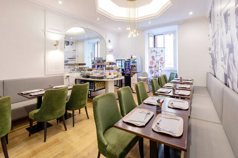 Dining area with wooden tables, green chairs, gray benches, buffet counter, and coffee machines at B&B Hotel Roma Italia Viminale