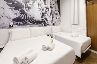 Two white beds with rolled towels on each in a room featuring a black and white statue mural at B&B Hotel Roma Italia Viminale