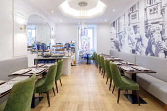 Dining area with green chairs, wooden tables set with plates and cutlery, buffet table, and wall art at B&B Hotel Roma Italia Viminale
