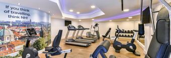 Fitness room at NH Hotel M&uuml;nchen Neue Messe with treadmills, exercise bikes, weight rack, and motivational cityscape wall art