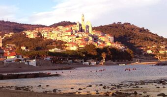 Paesaggio di un villaggio costiero al tramonto con vista su colline ed edifici, pubblicit&agrave; della Pensione Ristorante Bellavista.