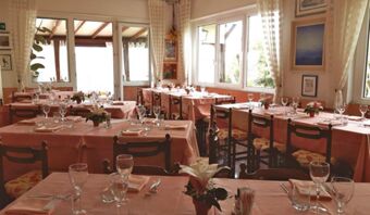 La luminosa sala da pranzo della Pensione Ristorante Bellavista, con tavoli coperti e grandi finestre, invita gli ospiti.