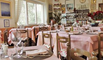 Vista interna dell'accogliente sala da pranzo della Pensione Ristorante Bellavista con tavoli apparecchiati e quadri decorativi alle pareti.