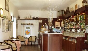 Accogliente bar con bancone in legno, scaffali pieni di bottiglie e posti a sedere nella Pensione Ristorante Bellavista.