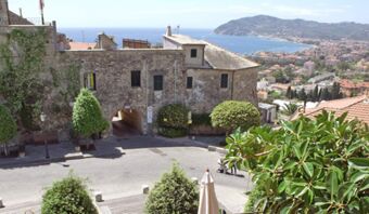 Vista di un gruppo di edifici in pietra con archi e alberi e del panorama costiero della Pensione Ristorante Bellavista in Italia.