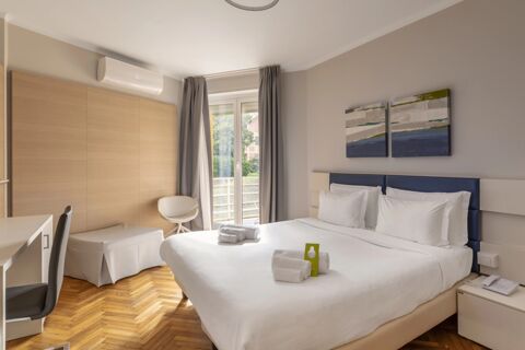Bright hotel room at B&B Hotel Park Hotel Suisse Santa Margherita Ligure with a double bed, wooden floor, desk, and balcony window
