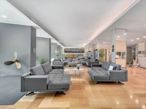 A large modern lobby area with multiple gray sofas, small tables, plants, and mirrored pillars at B&B Hotel Park Hotel Suisse Santa Margherita Ligure