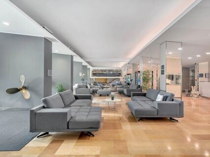 A large modern lobby area with multiple gray sofas, small tables, plants, and mirrored pillars at B&B Hotel Park Hotel Suisse Santa Margherita Ligure