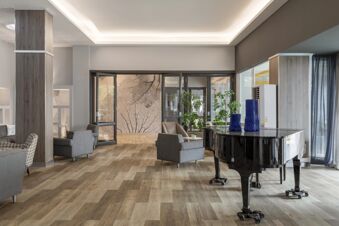 Spacious lobby at B&B Hotel Park Hotel Suisse Santa Margherita Ligure featuring a black grand piano, gray armchairs, and plants