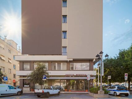 Front view of B&B Hotel Riviera Celle Ligure showing the building facade with windows, parked cars, street lamps, and trees