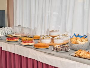 Breakfast buffet with pastries, cakes, bread, cold cuts, jam, and cups arranged on a table at B&B Hotel Riviera Celle Ligure