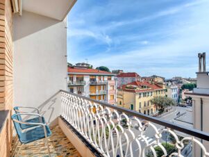 Balcony with two blue chairs and patterned tile floor overlooking buildings and street at B&B Hotel Riviera Celle Ligure