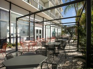 Outdoor seating area with black and red metal tables and chairs under a black metal frame at B&B Hotel Savona