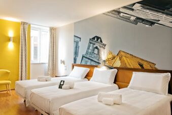 Three neatly made single beds with white linens and rolled towels in a bright room at B&B Hotel Palermo Quattro Canti