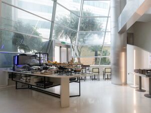 Buffet table with assorted pastries, bread, fruit, and breakfast appliances inside a bright room with large windows at B&B Hotel Trapani Crystal