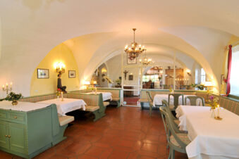 Dining area with arched ceilings, green wooden seating and tables with white cloths at Hotel Ansitz Tschindlhof