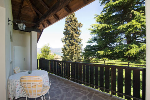 Balcony with table and two chairs overlooking trees and mountains at Hotel Ansitz Tschindlhof in sunlight