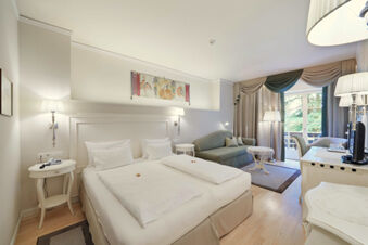 Hotel Ansitz Tschindlhof spacious room with double bed, sofa, two bedside tables, lamps, and balcony doors with curtains