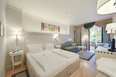 Hotel Ansitz Tschindlhof spacious room with double bed, sofa, two bedside tables, lamps, and balcony doors with curtains