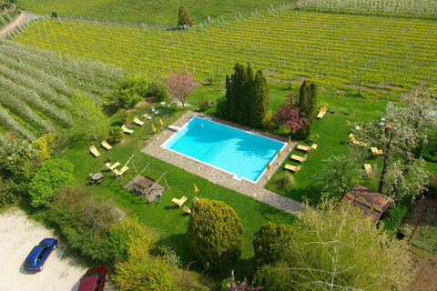 Outdoor swimming pool surrounded by lounge chairs and sun umbrellas in a green garden at Hotel Ansitz Tschindlhof