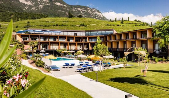 Hotel THALHOF am See outdoor pool area with sun loungers, umbrellas, garden, and mountain backdrop under clear sky
