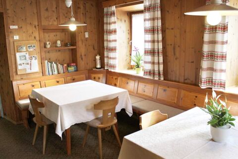 Accogliente zona pranzo con pareti in legno, tovaglie, piante e tende nel maso Innersieslhof, Villa Anna per un ambiente tradizionale.