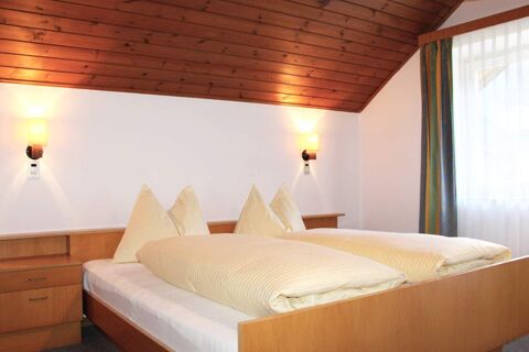 Camera da letto arredata in modo luminoso con mobili in legno e soffitto spiovente in legno nel maso Innersieslhof, Villa Anna con letto matrimoniale e due comodini.