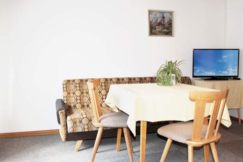 Accogliente zona pranzo con tavolo, sedie e divano in una camera del maso Innersieslhof, Villa Anna, con TV e murale.