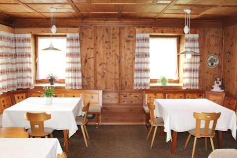 Accogliente zona pranzo con mobili in legno e tende a scacchiera nel casale Innersieslhof, Villa Anna con tovaglie bianche.