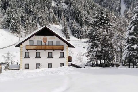 Vista esterna innevata del maso Innersieslhof, Villa Anna, circondata da alberi e montagne innevate in inverno.