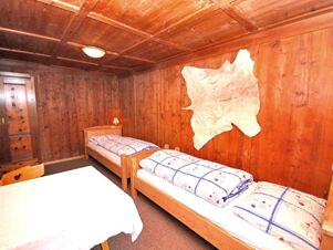 Rustikal eingerichtetes Zimmer mit zwei Einzelbetten und Holzvert&auml;felung im Bauernhof Villgrater am Ort, gem&uuml;tliche Atmosph&auml;re mit traditionellem Dekor.