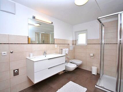 Moderne und helle Badezimmereinrichtung mit Dusche, WC, Bidet und gro&szlig;em Spiegel im Bauernhof Villgrater am Ort.