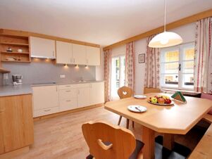 Helle K&uuml;che mit Holzdetails und Sitzbereich im Bauernhof Villgrater am Ort, ausgestattet mit Esstisch, St&uuml;hlen und modernen K&uuml;chenm&ouml;beln.