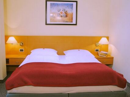 Уютна спалня с двойно легло, нощни лампи и картина над таблата на леглото в Apparthotel Central.