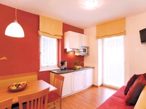 Светъл и уютен кухненски бокс с кът за хранене и диван в Apparthotel Central, модерен дизайн с червени и жълти акценти.