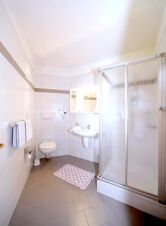 Moderne, rent bad med dusj, toalett og servant p&aring; Hotel Waldheim, lyst og funksjonelt.