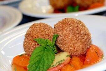 To spr&oslash;, panerte dumplings servert med friske mandariner og et mynteblad som garnityr p&aring; Hotel Waldheim.