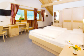 Hotel Gasthof Borest & Residence Riposo room with double bed, wooden furniture, desk, chairs, TV, window and flower vase