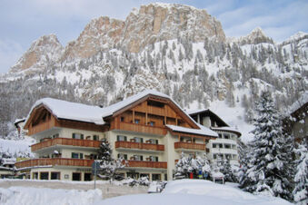 Hotel Gasthof Borest & Residence Riposo building with wooden balconies covered in snow at the base of snowy mountains
