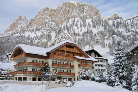 Hotel Gasthof Borest & Residence Riposo building with wooden balconies covered in snow at the base of snowy mountains