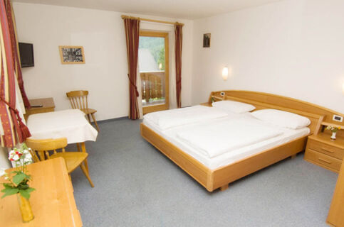 Hotel Gasthof Borest & Residence Riposo room with a double bed, small table with chairs, TV, balcony door, and simple decor